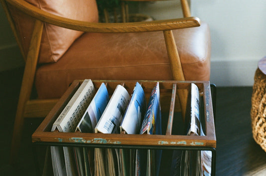 Wooden organizer with magazines next to leather chair.