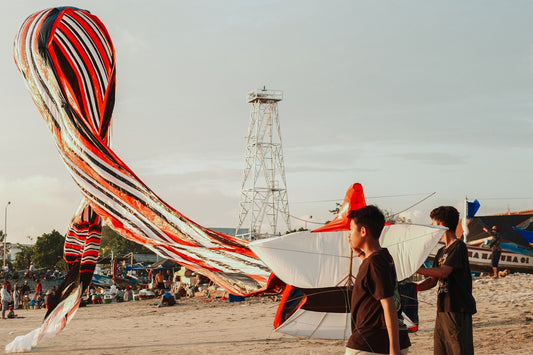 People prepare large kites on a sandy beach.