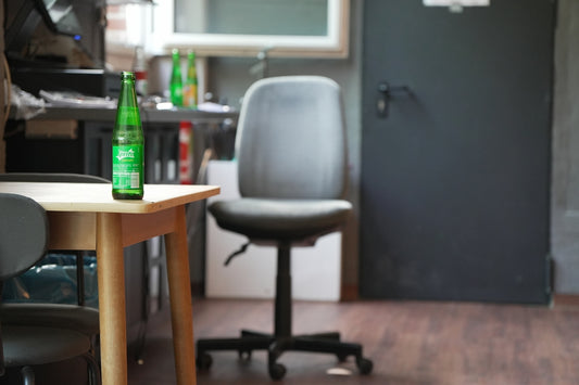 A green bottle and grey office chair in a room.